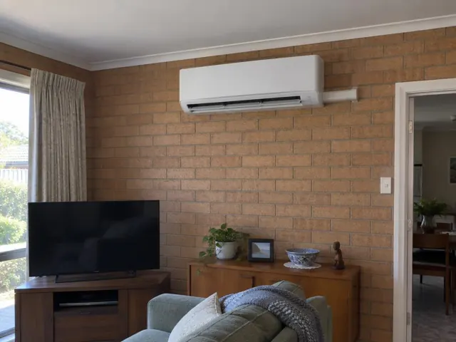 Split system mounted high on a brick living room wall above a sideboard in Salisbury Plain